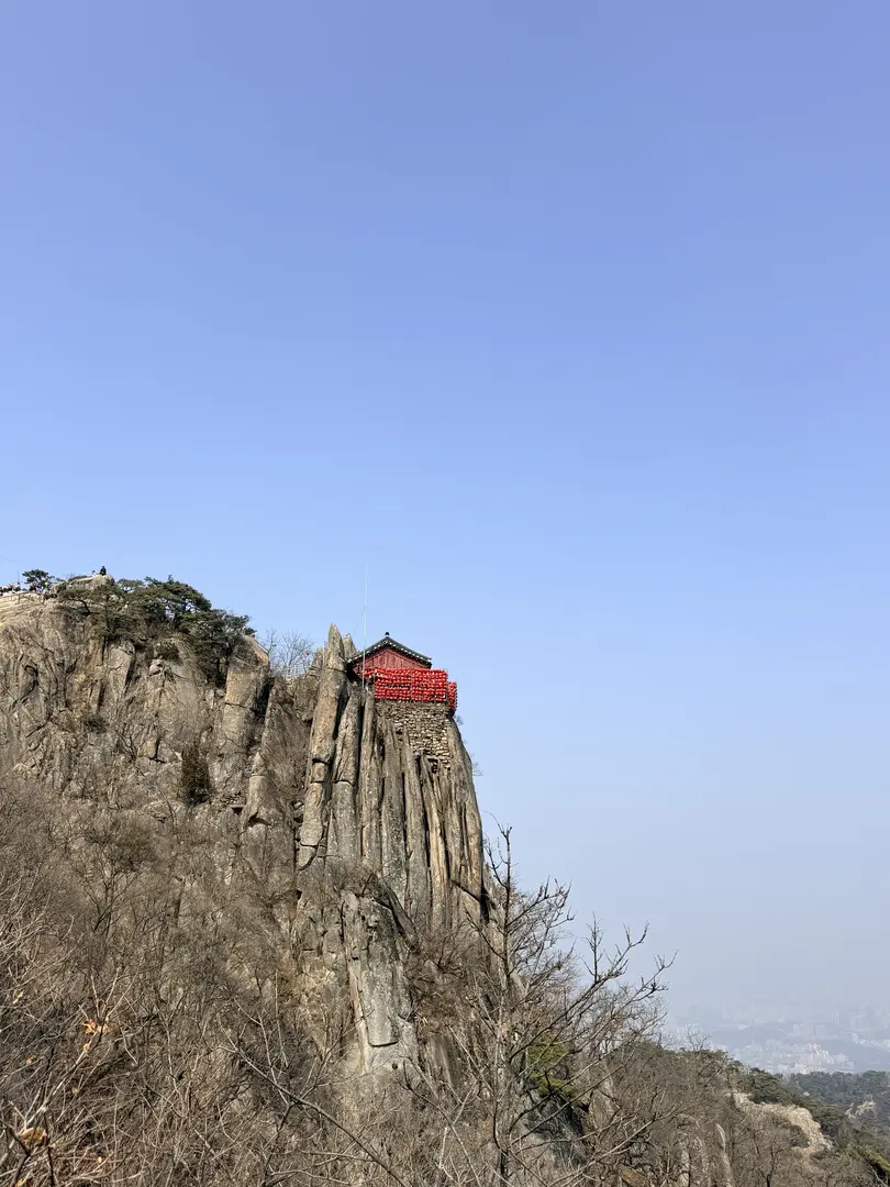 Red-roofed temple perched on dramatic rocky cliff outcrop