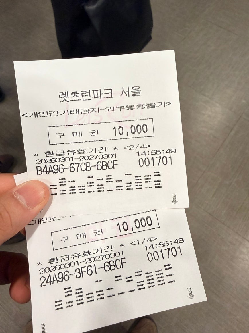 Two Let’s Run Park Seoul betting vouchers each showing 10,000 won face value held in hand, printed with alphanumeric codes and dates